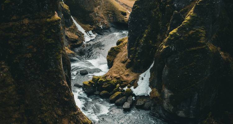 River cutting through moss-covered rocky canyon.