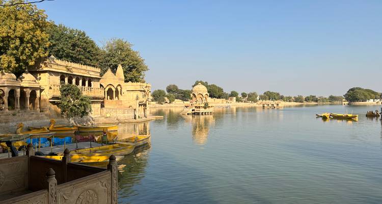 A tranquil lake with historical architecture and boats.