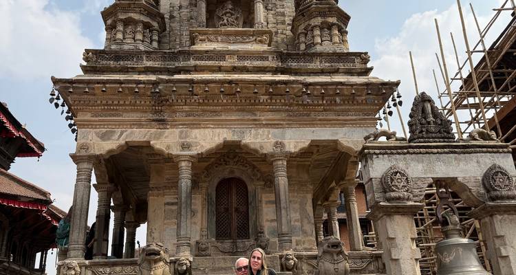 Two people pose in front of a historic temple.