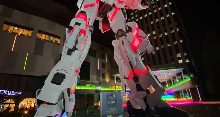 Grande statue de Gundam éclairée la nuit.