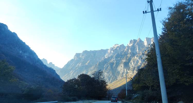 A car driving on a road surrounded by majestic mountains.