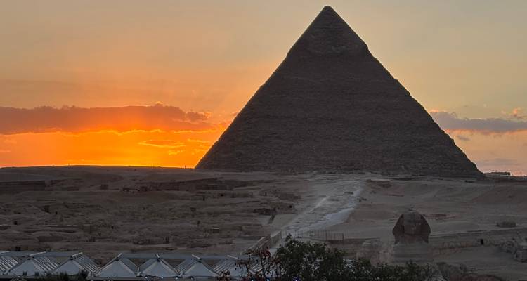 Zonsondergang achter de Grote Piramide met de Sfinx op de voorgrond.
