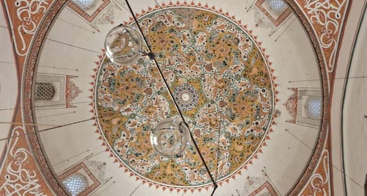 Intricately decorated dome ceiling with hanging lamps.