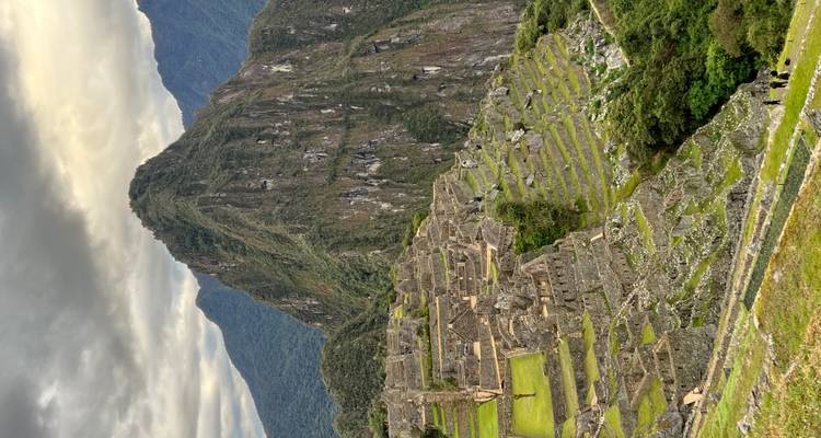 View of Machu Picchu with terraces and high peak.