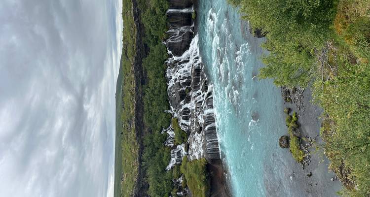 Prachtige waterval met turquoise water omringd door groen gebladerte.
