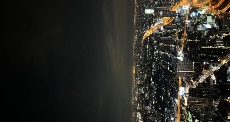 Paysage urbain de nuit avec des routes et des bâtiments illuminés.