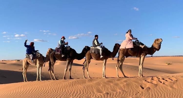 People riding camels in the desert.