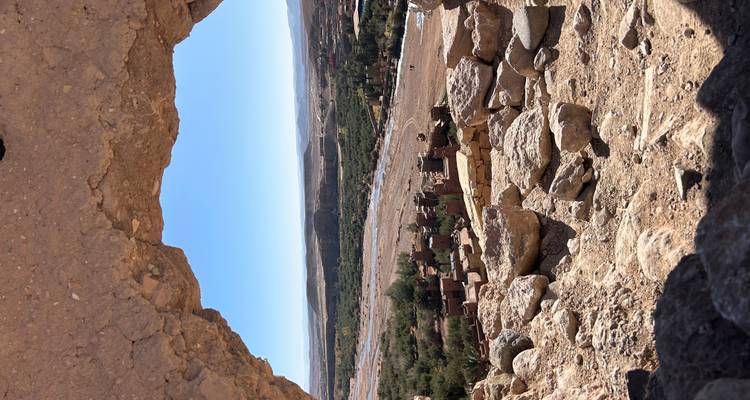 View through a rock frame of a lush green valley with a village and fields.
