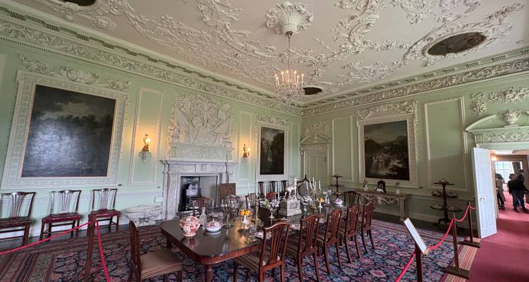 An ornate dining room with detailed ceiling and classic furniture.