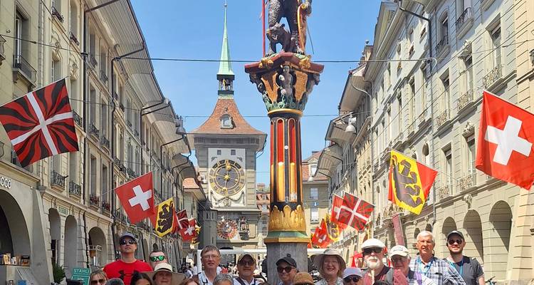 Touristes posant dans une rue historique avec des drapeaux suisses.