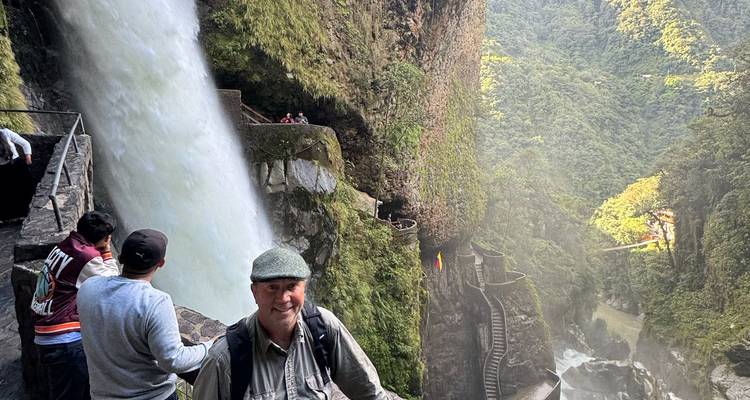 People visiting a waterfall in a lush forest setting.