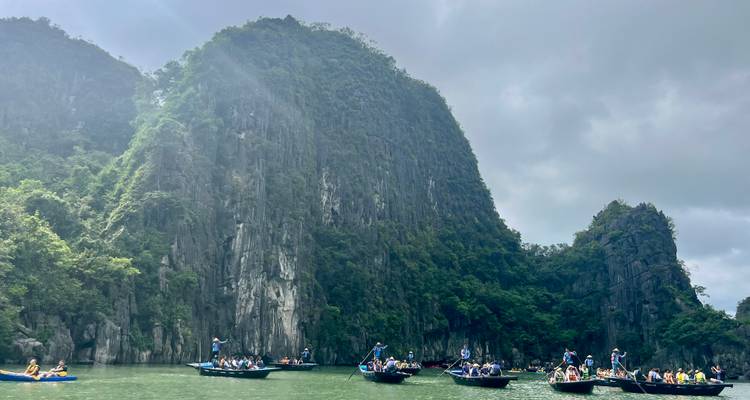 Tourists on boats surrounded by towering limestone cliffs.