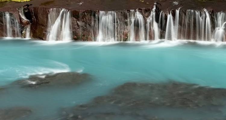 Des cascades d'un bleu éclatant cascadant sur des rochers sombres.