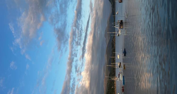 Voiliers sur une eau calme avec des montagnes en arrière-plan.