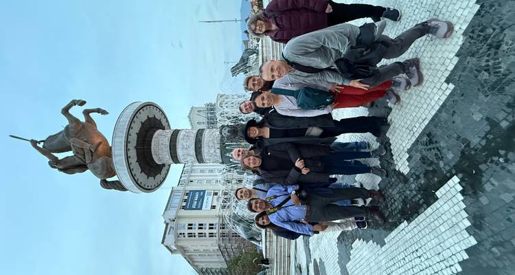 Groupe de touristes debout devant une grande statue et une fontaine.