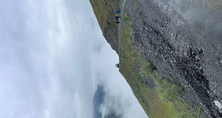 Des gens qui marchent sur une route de montagne brumeuse.