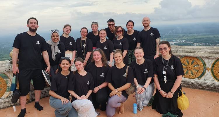 Group of tourists in matching shirts posing on a terrace.