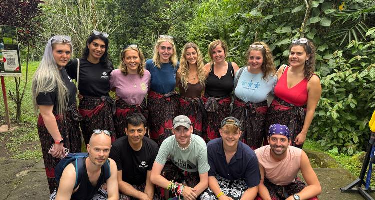 Group of tourists in sarongs in a lush jungle setting.