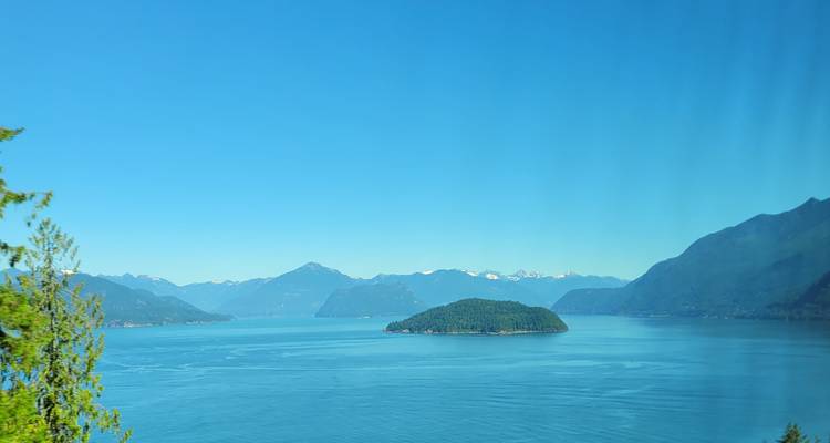 Vue panoramique d'un lac entouré de montagnes avec une île.