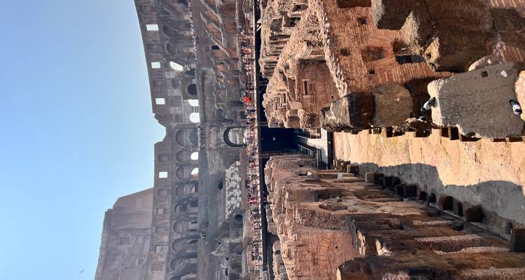 Arène centrale du Colisée avec des touristes marchant au niveau inférieur.
