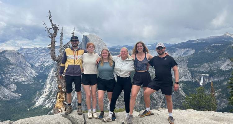 Groupe de personnes à un point de vue en montagne avec Half Dome en arrière-plan.