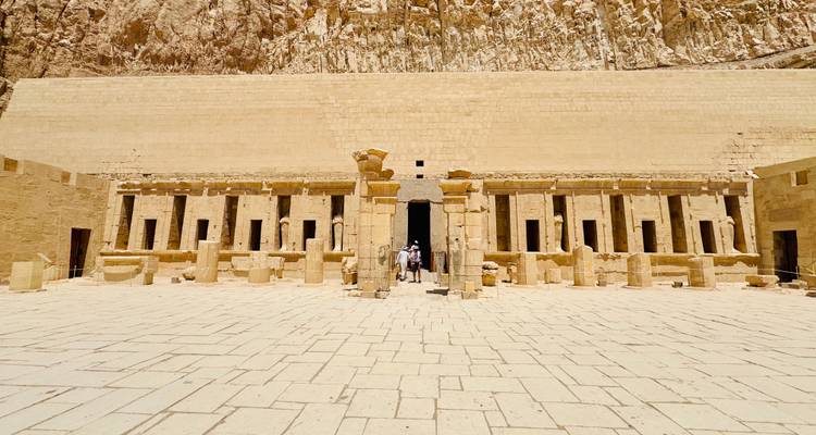 Entrance of an ancient temple with columns and a few visitors.