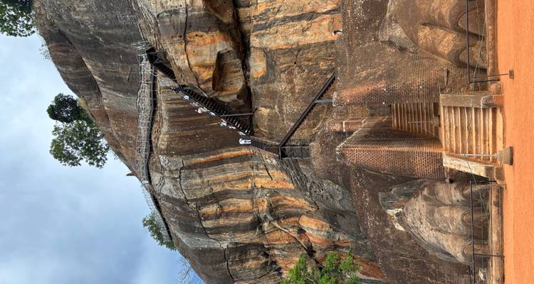 People climbing a staircase built into a large rock.