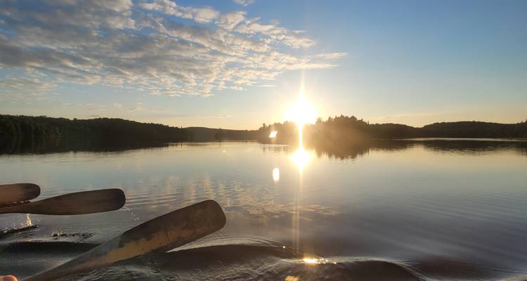 Pagayer en canoë avec un coucher de soleil sur un lac tranquille.