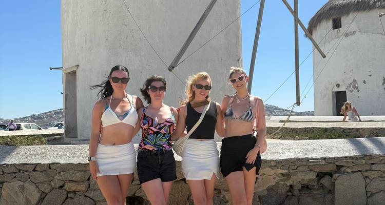 Quatre femmes posant par une journée ensoleillée devant des moulins à vent traditionnels.