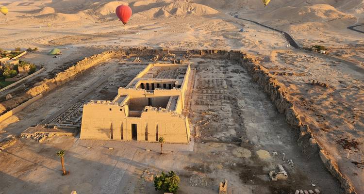 Aerial view of a desert temple complex with hot air balloons.