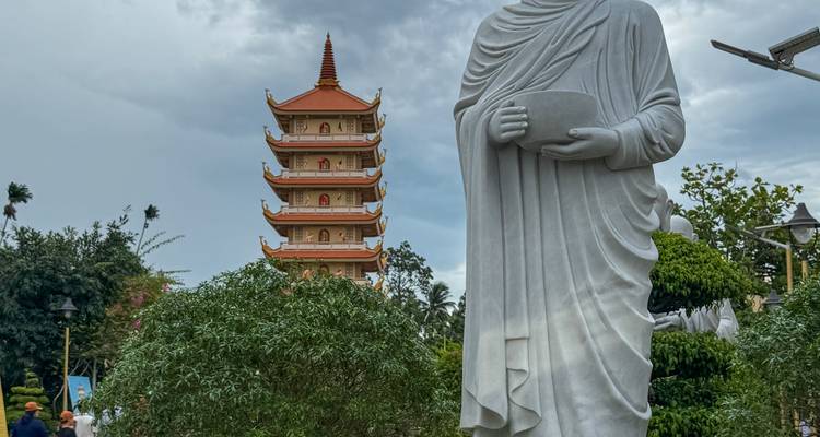 Statue of a deity standing in front of a pagoda.