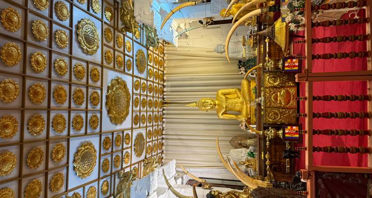 Interior view of a temple with a golden Buddha statue and elaborate decorations.