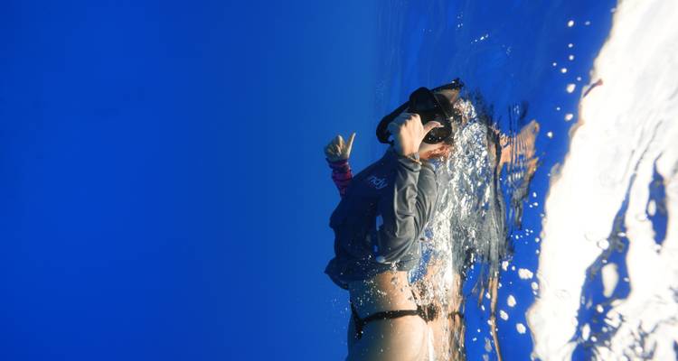 Person snorkeling underwater in clear blue waters.