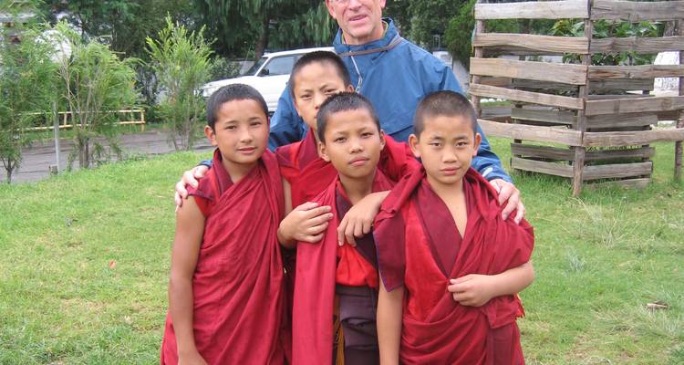 Group of young monks in red robes posing with a man.
