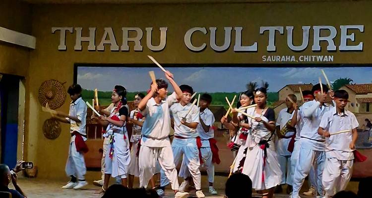 Cultural dance performance on a stage with 'Tharu Culture' signage.