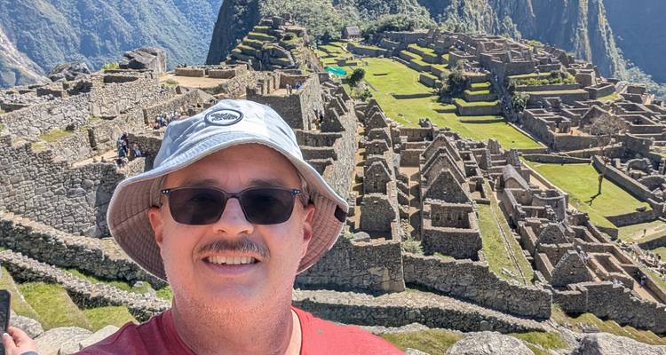 Man taking a selfie at Machu Picchu with ruins in the background.
