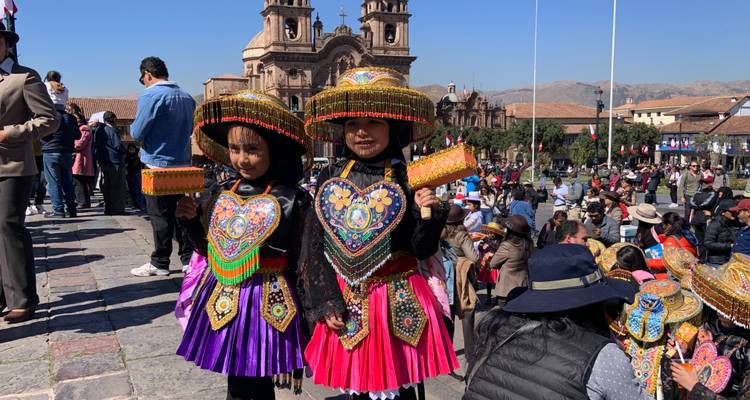 Children in traditional Peruvian costumes in a plaza.