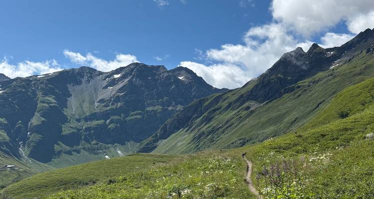 Green mountains with a dirt trail leading into the distance.