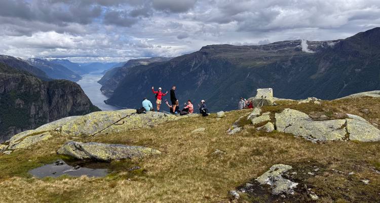 Groupe de randonneurs sur une montagne surplombant un fjord.