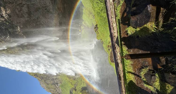 Cascada creando un arcoíris en un entorno verde y exuberante.