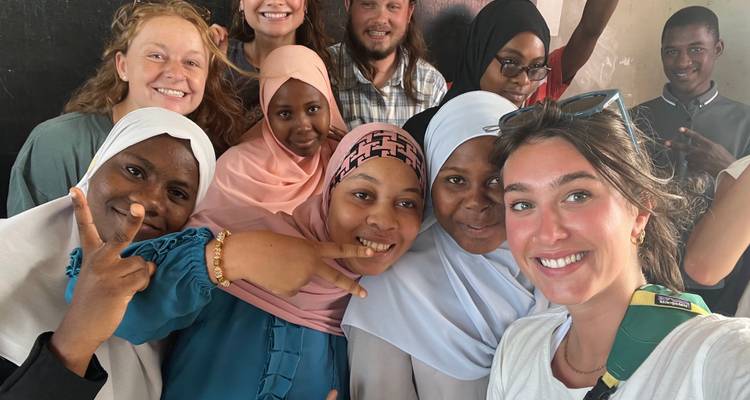 Groupe souriant de personnes, incluant des habitants locaux, posant ensemble pour un selfie.