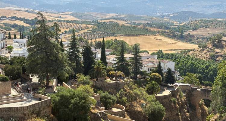 Une vue panoramique de collines, de champs et d'un pont, avec des montagnes au loin.