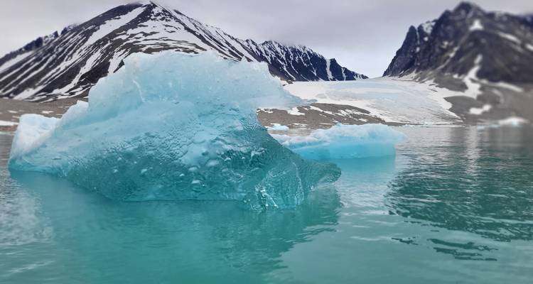 Close-up of an iceberg against a mountainous backdrop.