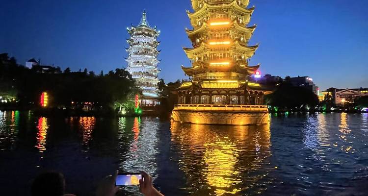 Illuminated pagodas reflecting in a lake at night.