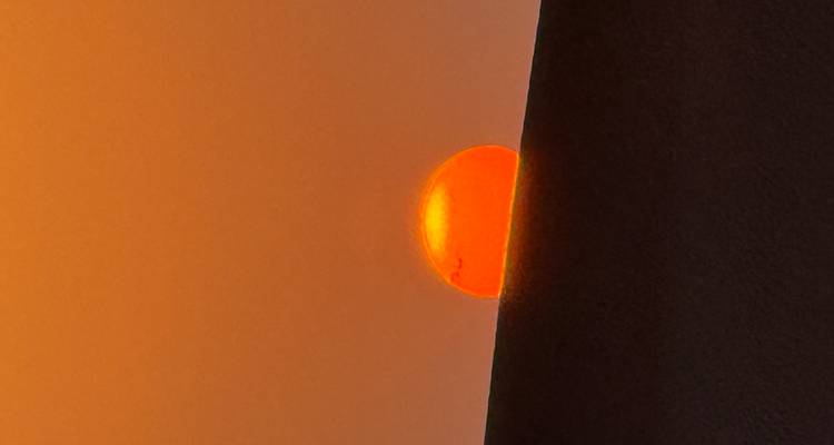 Sun setting behind a sand dune