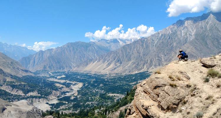 Person sitting on a cliff with a vast valley view
