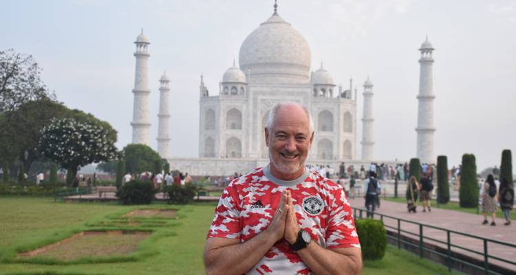 Hombre posando frente al Taj Mahal con las manos en oración.