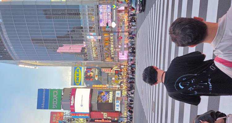 Carrefour animé de Shibuya avec des foules et des immeubles imposants.