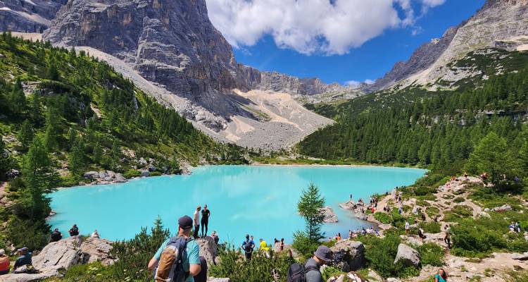 Turquoise lake in a scenic mountain setting with people enjoying the view.