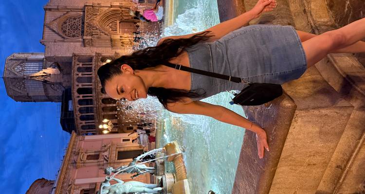 Femme à une fontaine dans un cadre nocturne vibrant, souriante.